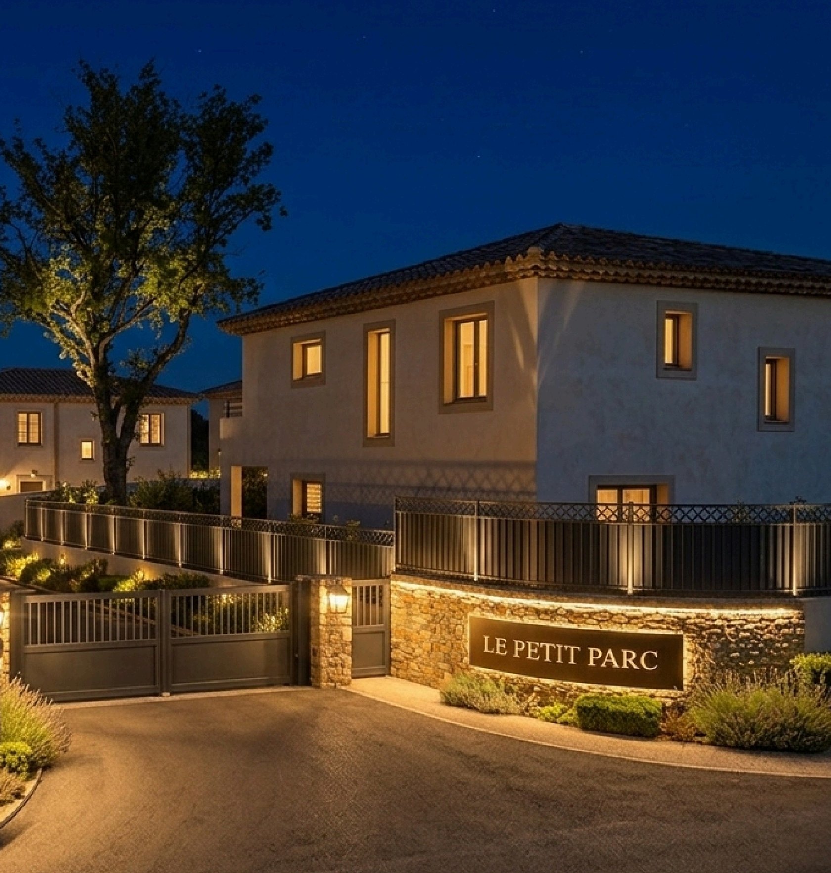 Rendu nocturne du lotissement Le Petit Parc : villas méditerranéennes éclairées derrière un portail en pierre